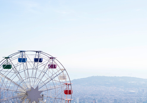 Ferris wheel with multi-colored cabs on a background of blue sky
