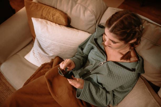 istock Young woman using a smart phone sitting on a sofa 1282280935