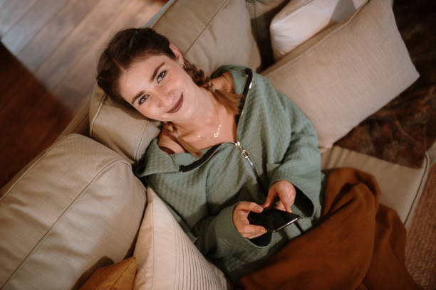 istock Young woman using a smart phone sitting on a sofa 1282281144