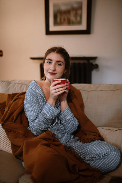 istock Young woman with a cup sitting on a sofa 1282282163