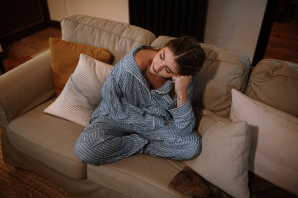 istock Young woman wearing a pajamas sitting on a sofa 1282282355