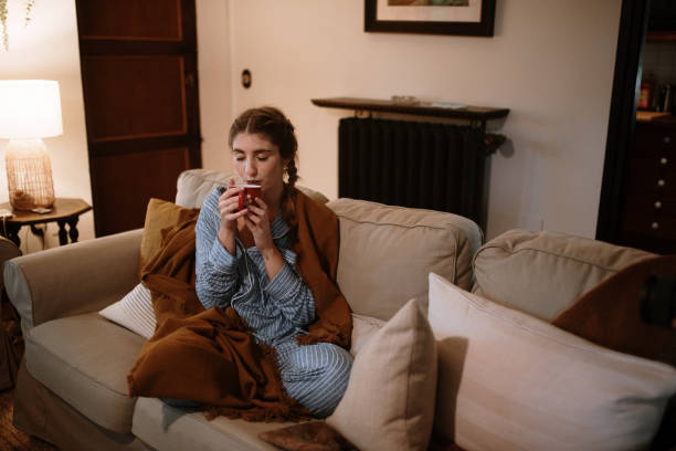 istock Young woman with a cup sitting on a sofa 1282282375