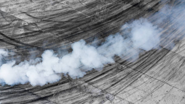 marques de pneus noires et fumée blanche sur la piste de course d’asphalte, nuage de poussière de route de voiture de conduite, fumées de combustion du tuyau d’échappement de voiture, le moteur ne fonctionne pas correctement. - tire track track asphalt skidding photos et images de collection