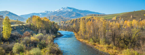 istock River, forested banks and a snow-capped peak. Sunny autumn day. Panoramic. 1282285668