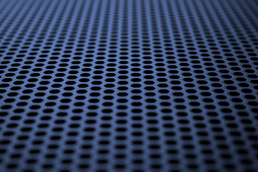Industrial background. Deep blue metal surface with regular round holes (abstract)