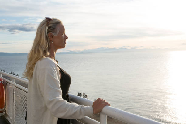 istock Woman looks out over calm ocean bay from railing 1282286036