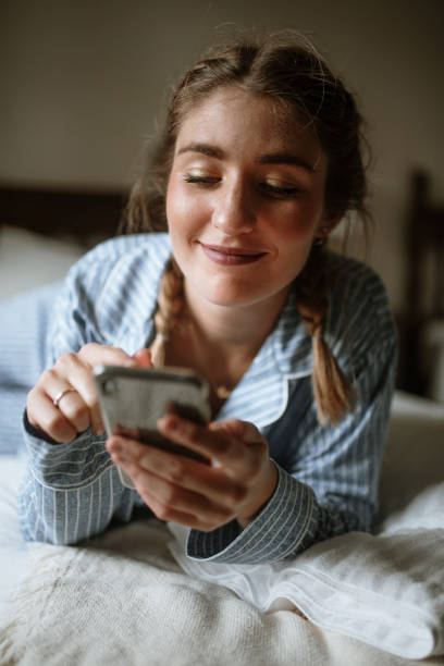 istock Young woman using a smart phone on a bed 1282288446