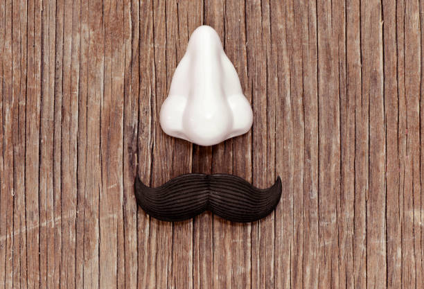 a fake nose and a fake mustache on a rustic wooden surface, depicting a man face