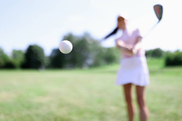 golfball vor dem hintergrund der schlagenden frau nahaufnahme - putting golf golfer golf swing stock-fotos und bilder