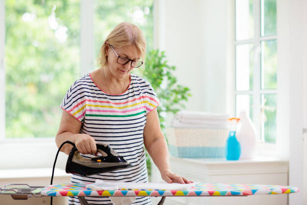 женщина гладит одежду. домашние дела. - iron women ironing board stereotypical housewife стоковые фото и изображения