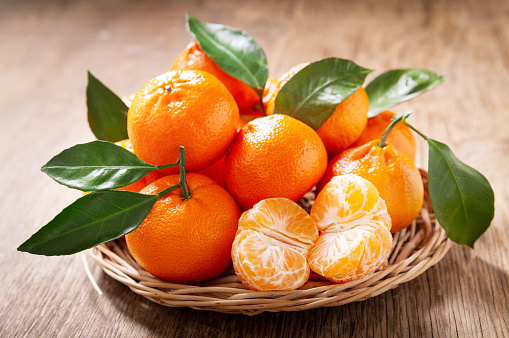 Fresh mandarin oranges fruit or tangerines with leaves on a wooden table