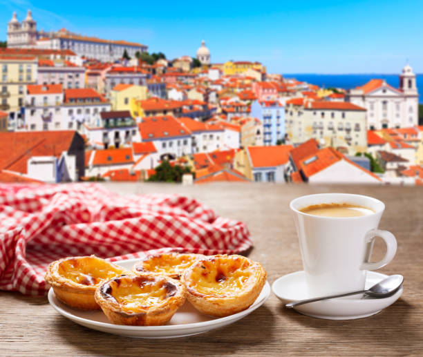 cup of coffee and plate of portuguese pastries - Pastel de nata, over Alfama district, lisbon, Portugal stock photo