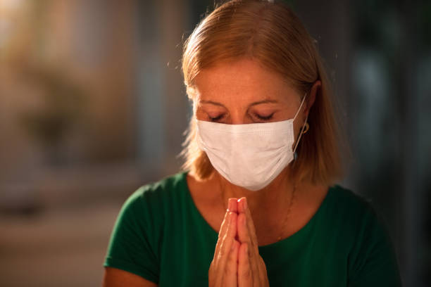 istock Woman in face mask praying for 1282292404