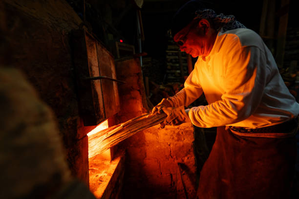 istock Senior pottery craftsmen adding firewood to his large kiln 1282292530