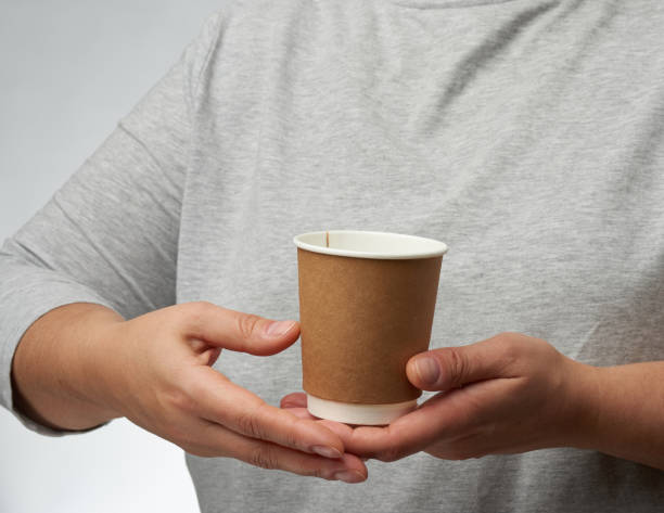 istock female hand holds paper brown disposable cup for coffee and tea 1282292690