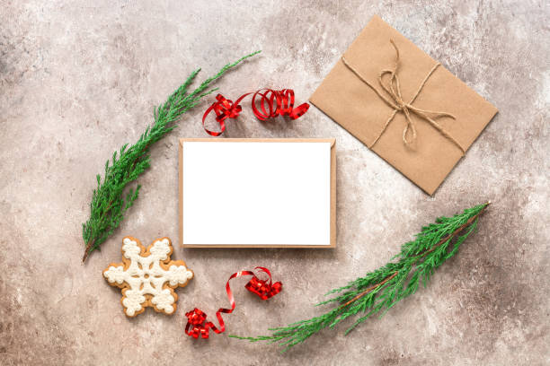 istock Christmas composition. Blank card mockup, fir branches, letter in craft envelope, gingerbread snowflake. Christmas card template. Top view, flat lay. Beige textured grunge background. 1282295598