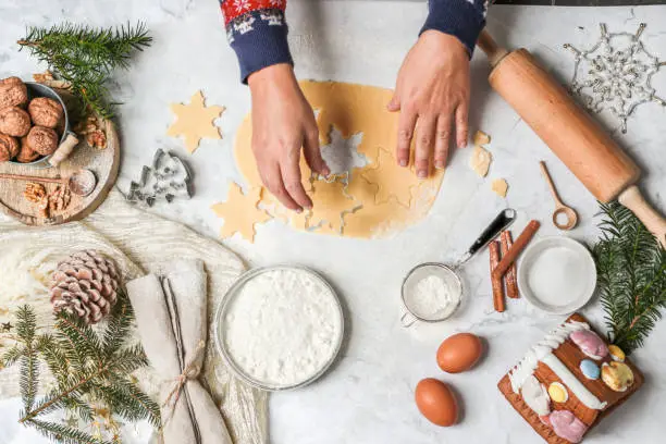 Baking homemade Christmas cookies on white marble kitchen table.