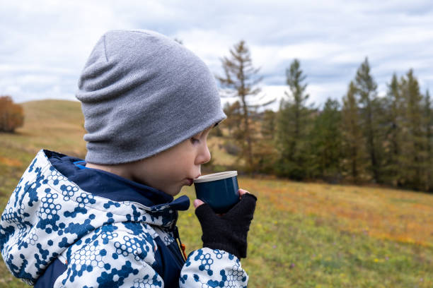 istock Little boy drinking hot tea Outdoors from a Insulated Drink Container 1282296807