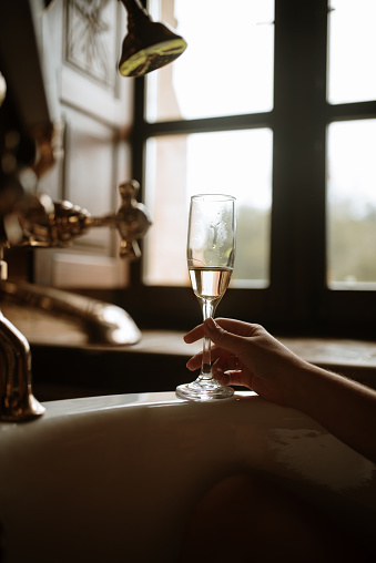 Young woman drinking champagne in a bathtub at home