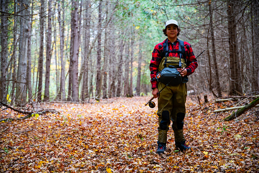 A young fisherman on a trail in soft autumn light.