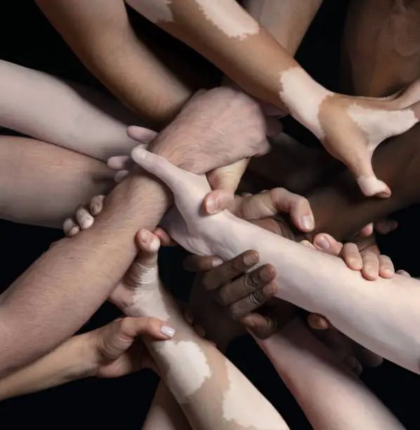 Photo of Hands of different people in touch isolated on black studio background. Concept of human relation, community, togetherness, inclusion