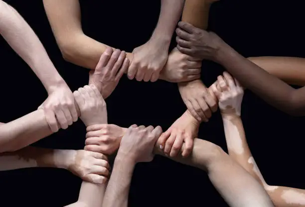 Photo of Hands of different people in touch isolated on black studio background. Concept of human relation, community, togetherness, inclusion