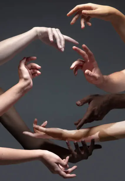 Photo of Hands of different people in touch isolated on grey studio background. Concept of human relation, community, togetherness, inclusion