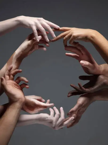 Photo of Hands of different people in touch isolated on grey studio background. Concept of human relation, community, togetherness, inclusion