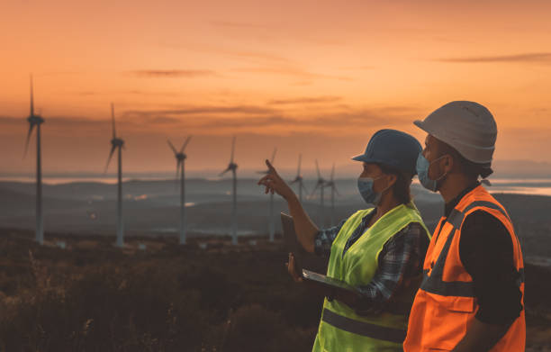 istock Maintenance engineer team with face mask working in wind turbine farm at sunset during pancemic 1282302525