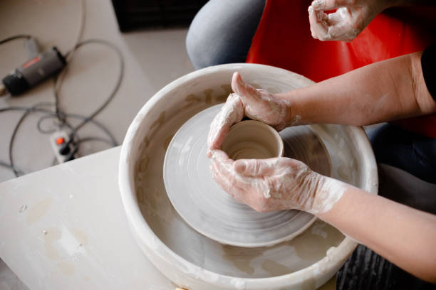 istock Female hands crafting a pottery cup on a potter's wheel. Handmade and crafting concept. 1282304708