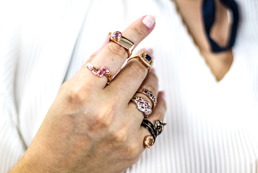 Elegant woman's hand full of rings of different colors and shapes. Various precious stones sapphire, ruby, diamond ...