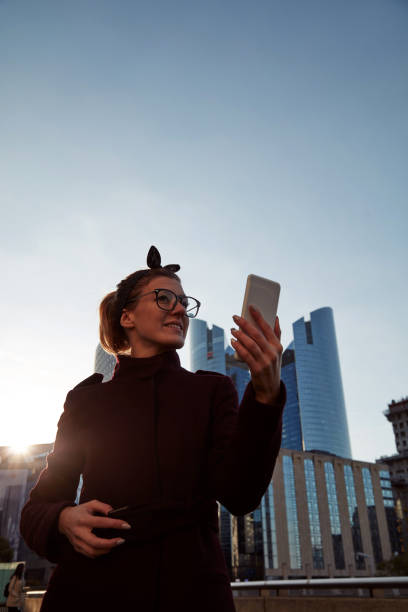 istock Woman using cellphone in urban surroundings with skyscrapers. 1282308885