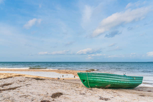 istock small green boat on empty sand beach against sea 1282308934
