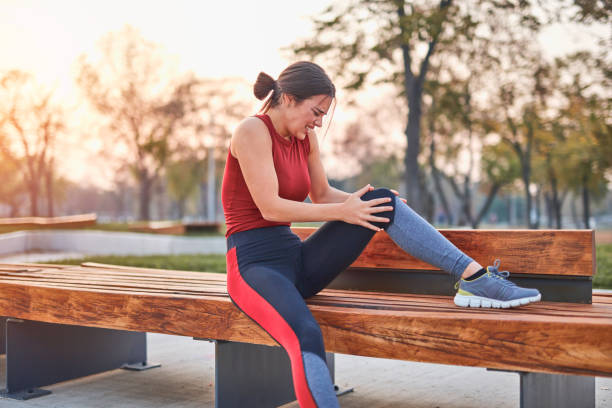 junge sportlerin mit schmerzen / verletzungen beim training und joggen im park. - sportlerin stock-fotos und bilder