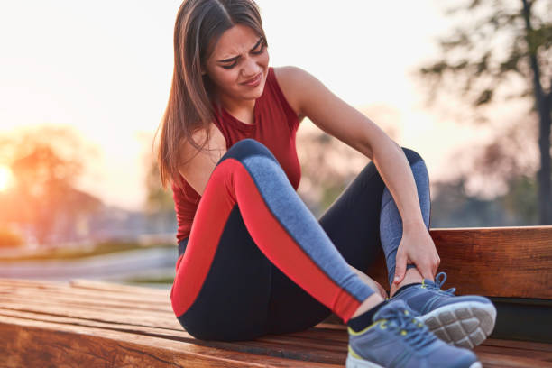 young sportswoman having pain / injury during exercise and jogging in the park. - twisted ankle fotos imagens e fotografias de stock