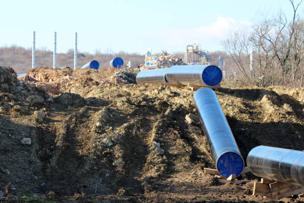 istock Construction site for new oil pipeline with multiple large diameter pipes and industrial chimneys in background 1282309245