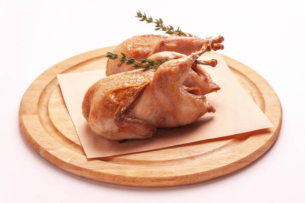 istock Fried quail on a wooden cutting board isolated on a white background. 1282310888