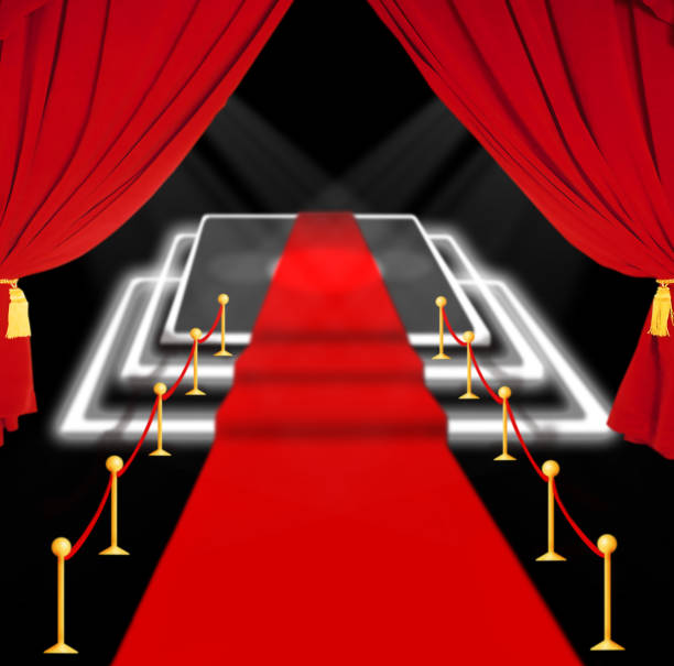 istock abstract blurred image. Red carpet with stairs between two rope barriers and flash light. Scene illuminated by a spotlight 1282311770
