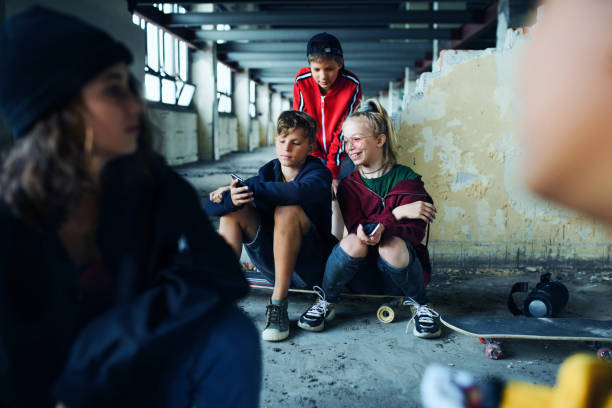 grupa nastolatków gang siedzi w pomieszczeniach w opuszczonym budynku, za pomocą smartfonów. - youth culture gang member adolescence family zdjęcia i obrazy z banku zdjęć