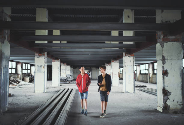 les garçons d’adolescents gang à l’intérieur dans le bâtiment abandonné, utilisant le smartphone. - youth culture gang member adolescence family photos et images de collection