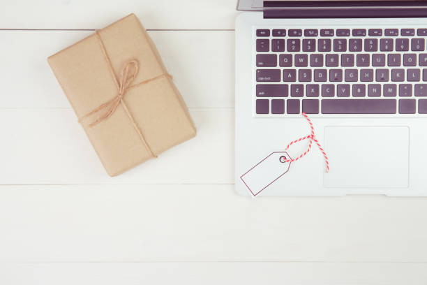 istock Gift box with paper kraft and having tag while laptop computer on wooden table, present giving for Christmas day or birthday, season and celebrate, top view, flat lay, online shopping concept. 1282312967