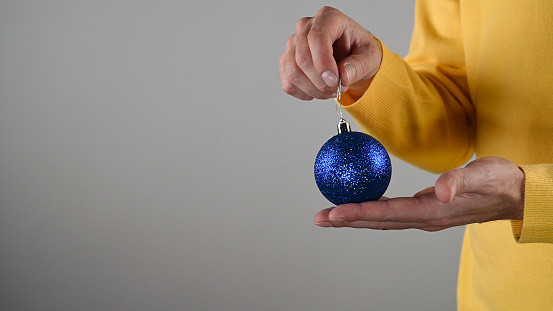 A man holding a blue christmas ball in his hand. High quality photo