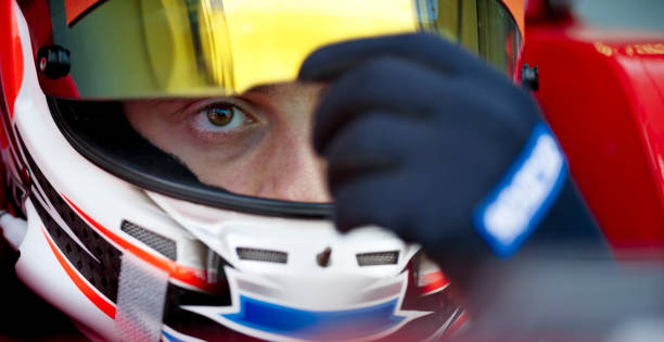 Driver wearing crash helmet and glove Close-up of concentrated racing driver wearing crash helmet and glove. race car driver stock pictures, royalty-free photos & images