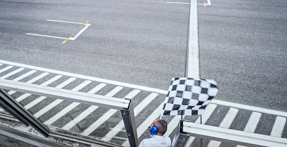 High angle view of auto race official waving chequered flag on track.