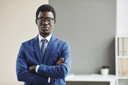 Portrait of African young businessman in eyeglasses and in formalwear standing with his arms crossed and looking at camera