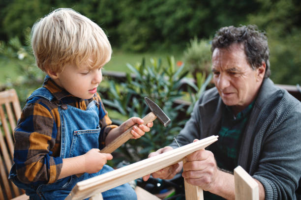 istock Small boy with senior grandfather constructing birdhouse, diy project. 1282315165