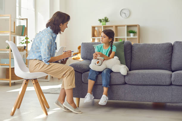 female child psychologist working with a little preschool girl in a bright office. - child therapy imagens e fotografias de stock