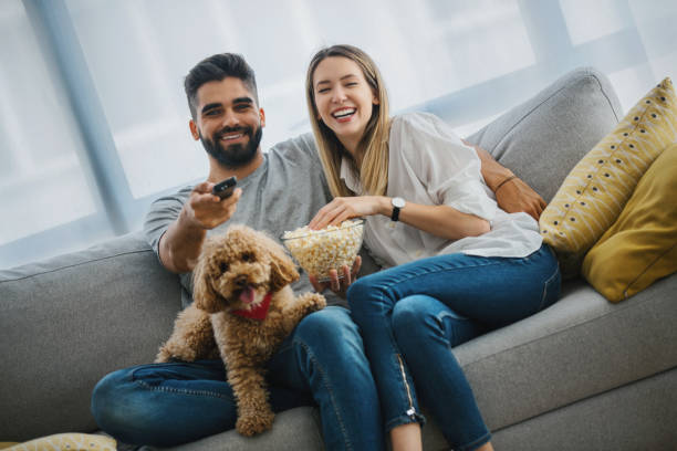 Young couple laughing while watching their favorite series on TV.