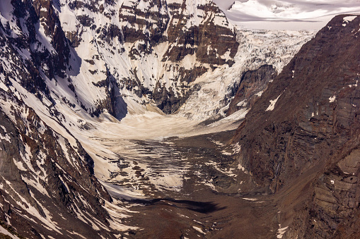 The rugged terrain of a glacier on a snow capped mountain at the Kunzum La pass in the Himalayan region of the Spiti Valley.