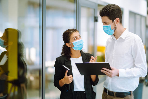 istock Two colleagues in protective face masks in modern office discussing together work issues. 1282321739